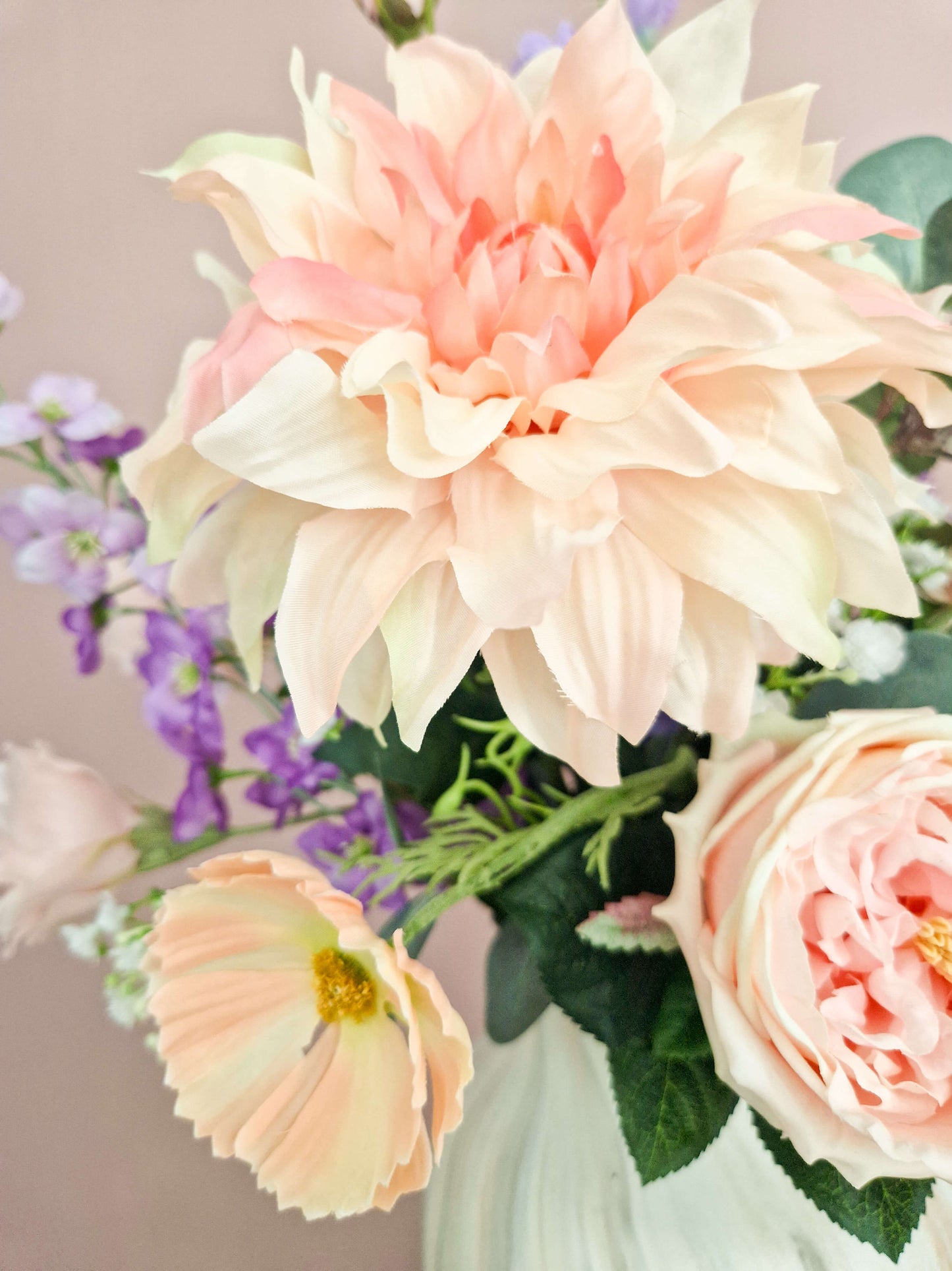 close up van een zacht roze zijden dahlia en roos in een herdenkingsboeket