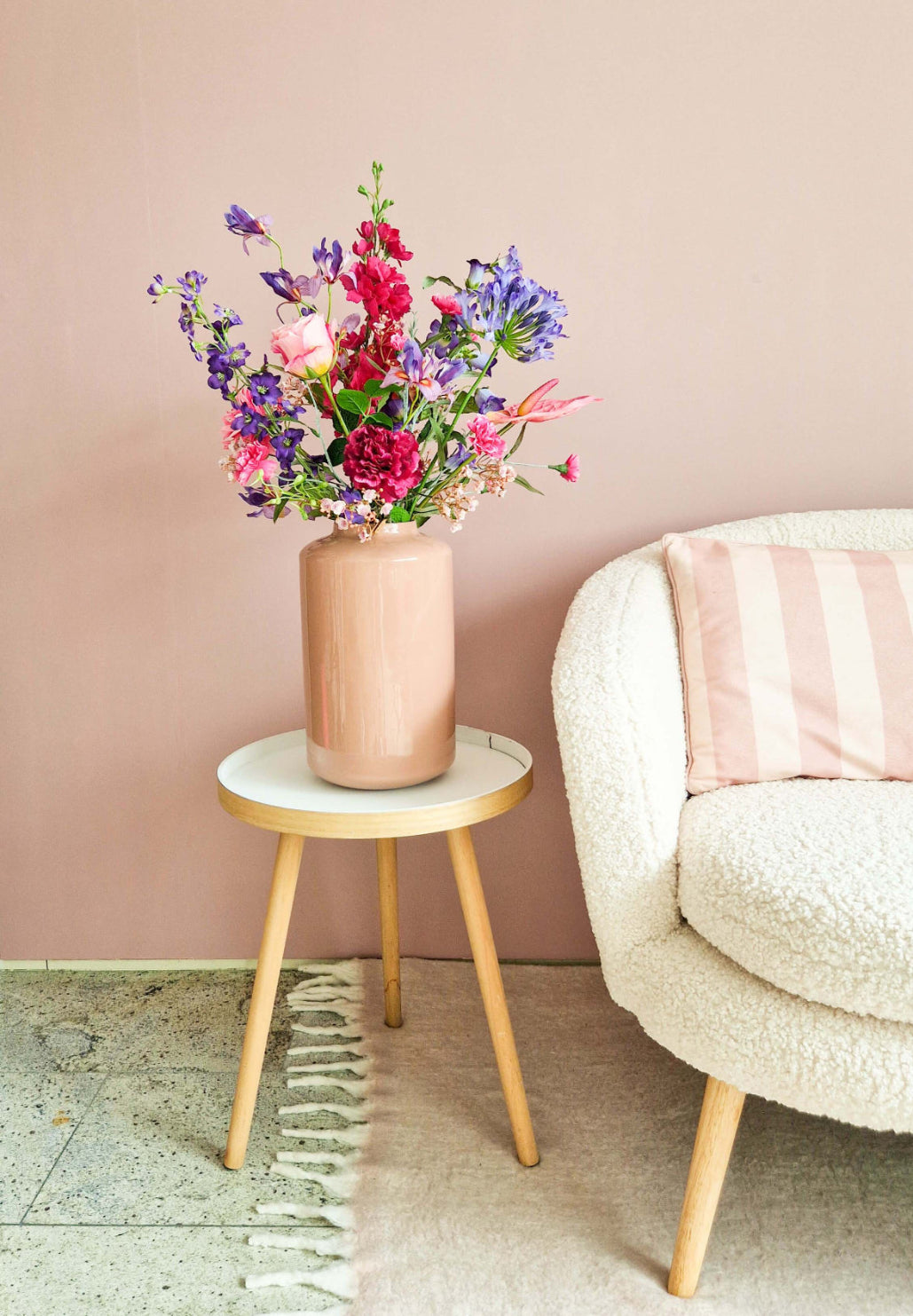 Zijden bloemenboeket met roze en paarse bloemen in roze vaas op een houten tafeltje