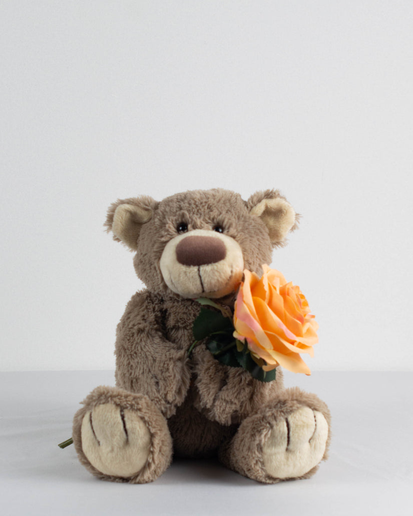 Troostbeer voor kinderen die een oranje zijden bloem vasthoudt