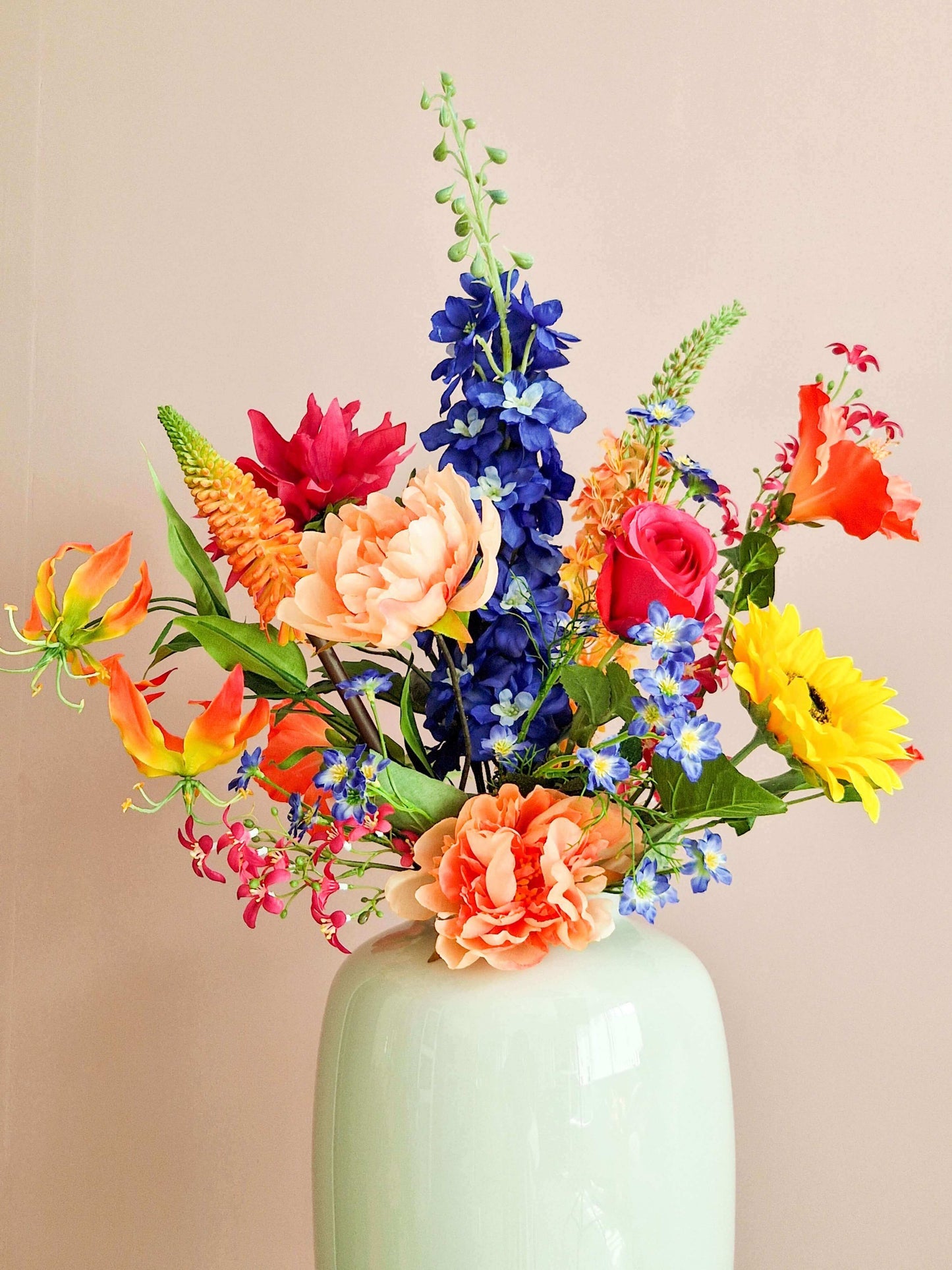 Kleurrijk zijden bloemenboeket met zonnebloemen, delphinium, gloriosa en rozen in witte vaas